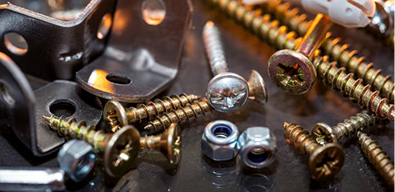 Close-up image of sets of plastic dowels and shiny metal self-tapping screws in a pile on a table background. Screws close up.